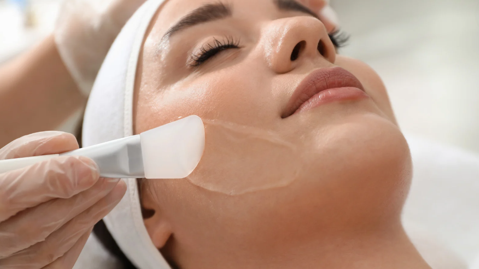 A professional at 4EvaGlow MedSpa in Lutz, Florida, applying a chemical peel solution to a patient’s face.